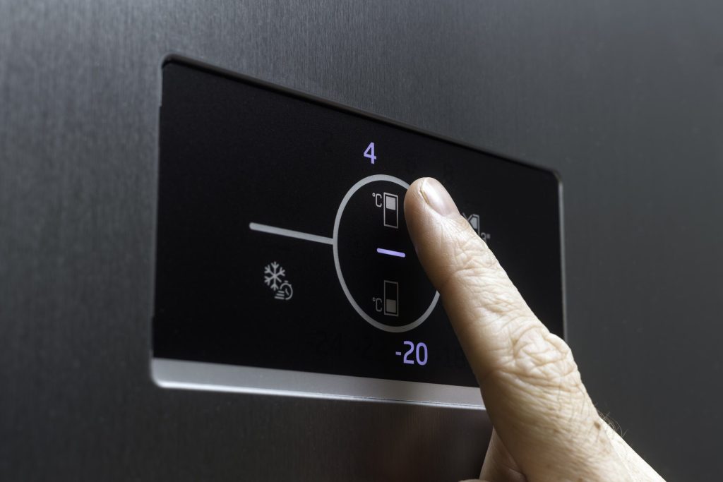 A finger setting the temperature on the touch panel of a refrigerator