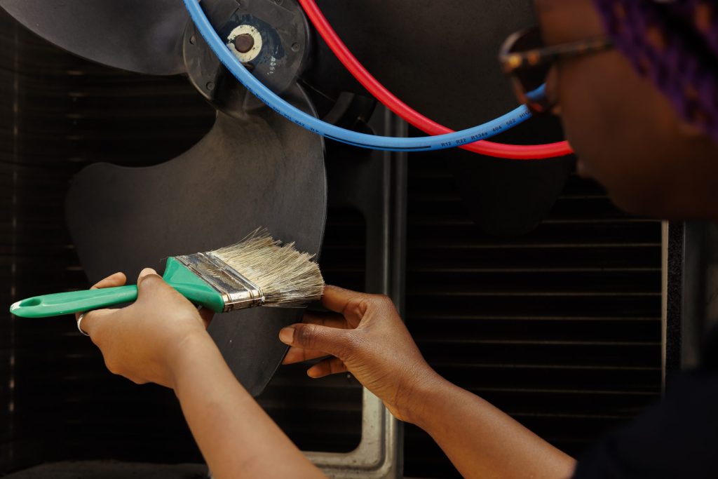 A brush working dust off a coil and fan behind an appliance