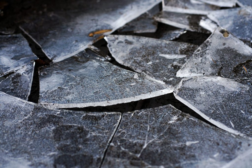 Cracked dark glass broken into sharp plates across a surface