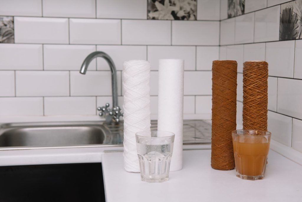 New and spent filter cartridges beside clear and discolored water