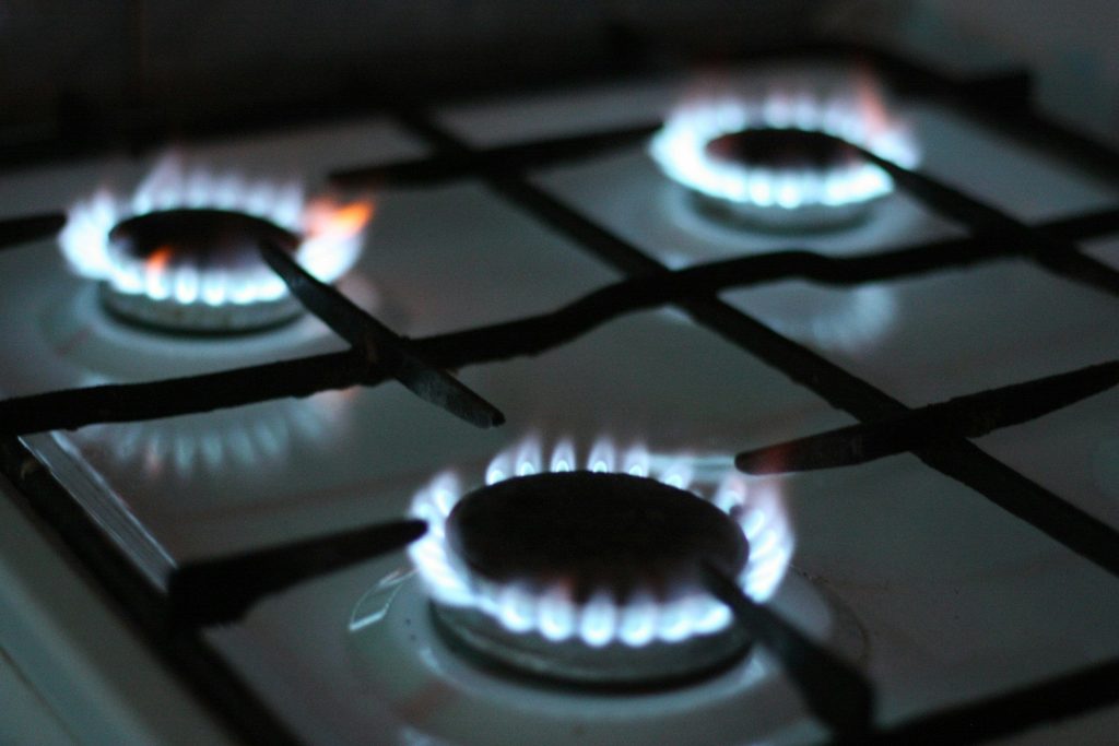 Three gas burners alight on a black hob with cast iron grates