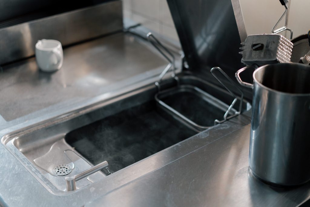 The open stainless interior of a professional ice machine with its scoop tray