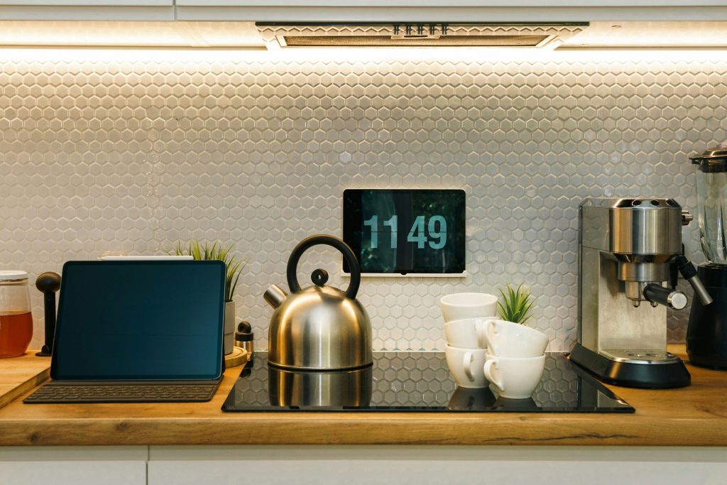 A worktop with an induction hob, a kettle on it, a tablet and a coffee machine either side