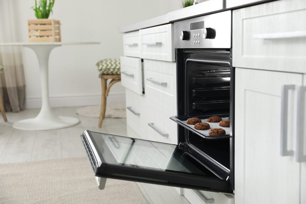 A tray of baked cookies on the open door of a wall oven