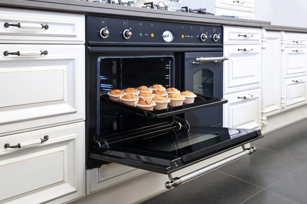 A black built-in oven open with a tray on the rack
