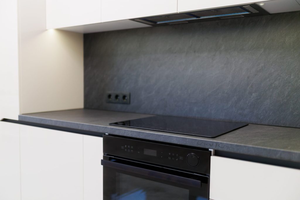 A black glass cooktop set into a slate worktop above a built-in oven