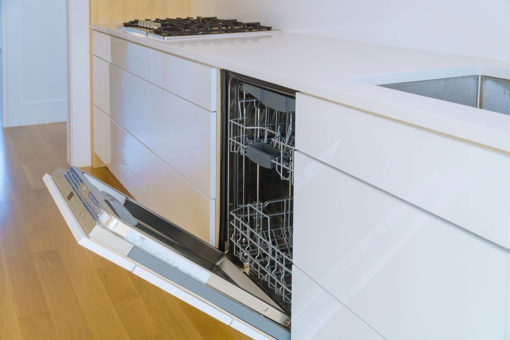 A dishwasher standing open in a light wood kitchen run