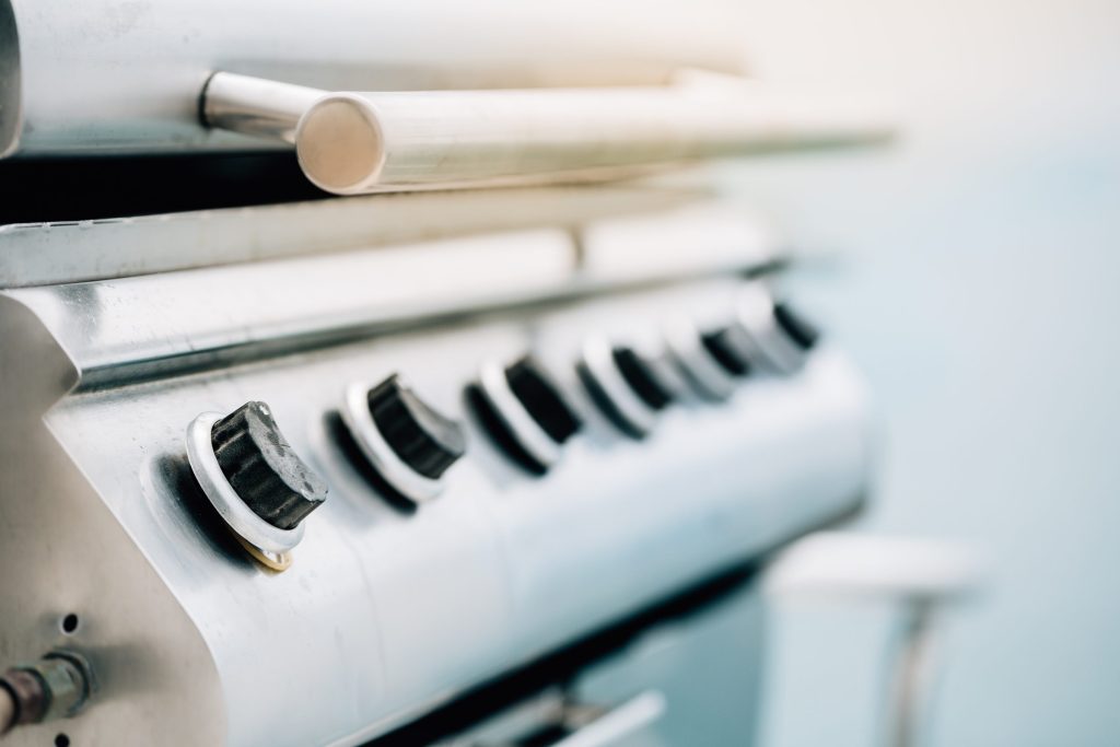 The control knobs along the front of a stainless gas grill
