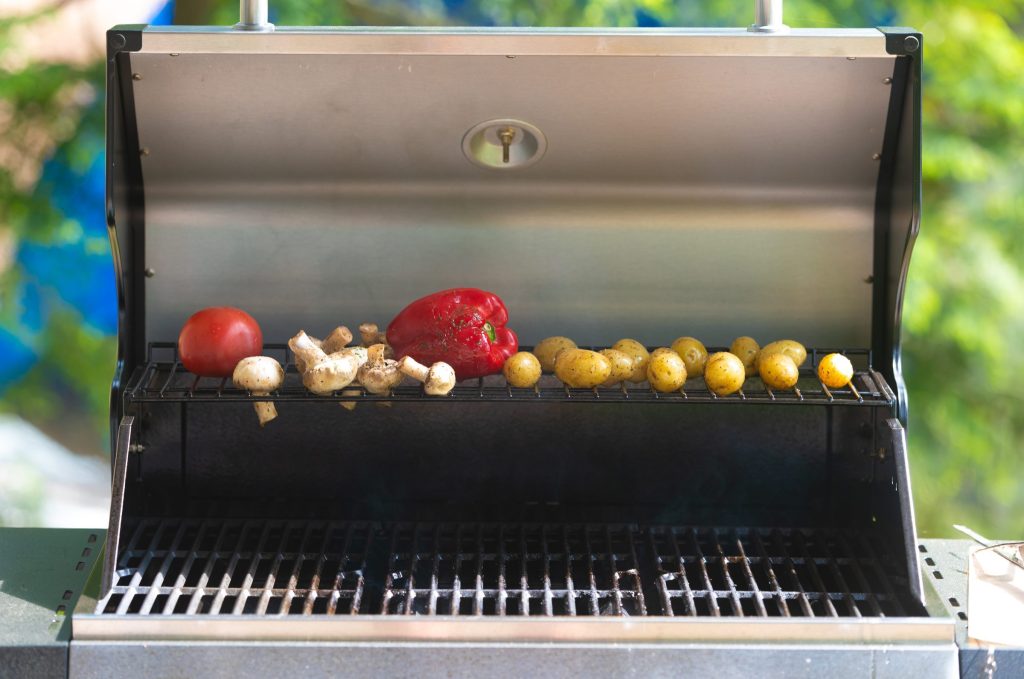 Peppers and onions on the grate of an open gas grill