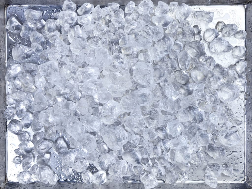 A steel bin filled to the rim with clear ice cubes