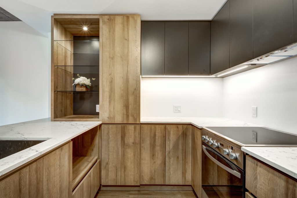 An oak galley kitchen with a flush cooktop and an oven under the counter