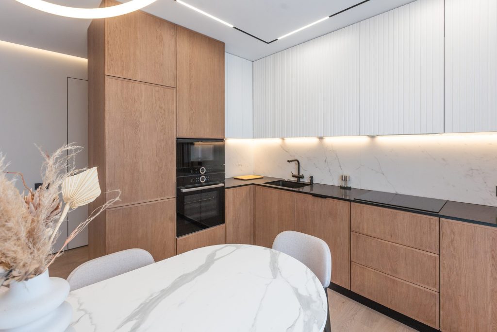 An oak and white kitchen run with a built-in oven beside a marble dining table