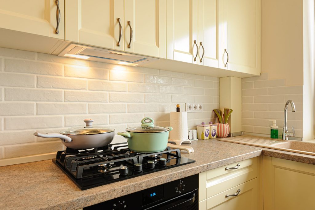 Two pans on a black hob in a stone counter