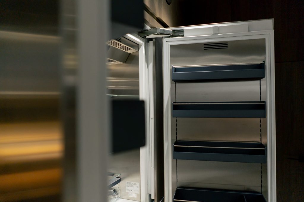 A stainless refrigerator standing open on empty steel shelves