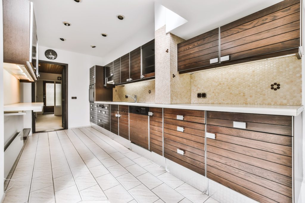 A narrow galley kitchen in dark stained wood with a honeycomb tile splashback and a black oven in the run