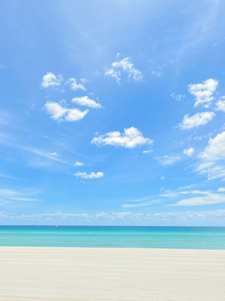 An empty stretch of white sand under a wide blue sky