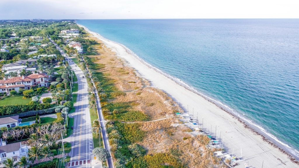 An aerial view of the beach, the road beside it and the houses behind