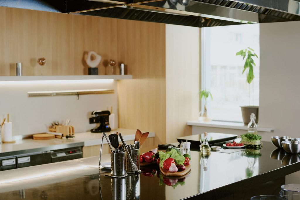 A black stone counter under a stainless canopy against a wood wall