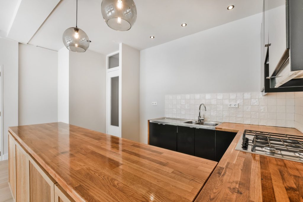A butcher block counter running past black cabinets and a gas hob