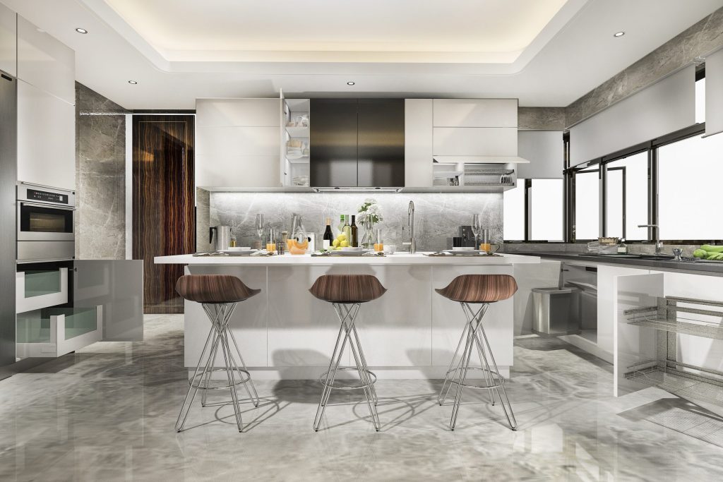 A grey marble kitchen with an island, stools and a run of tall cabinets