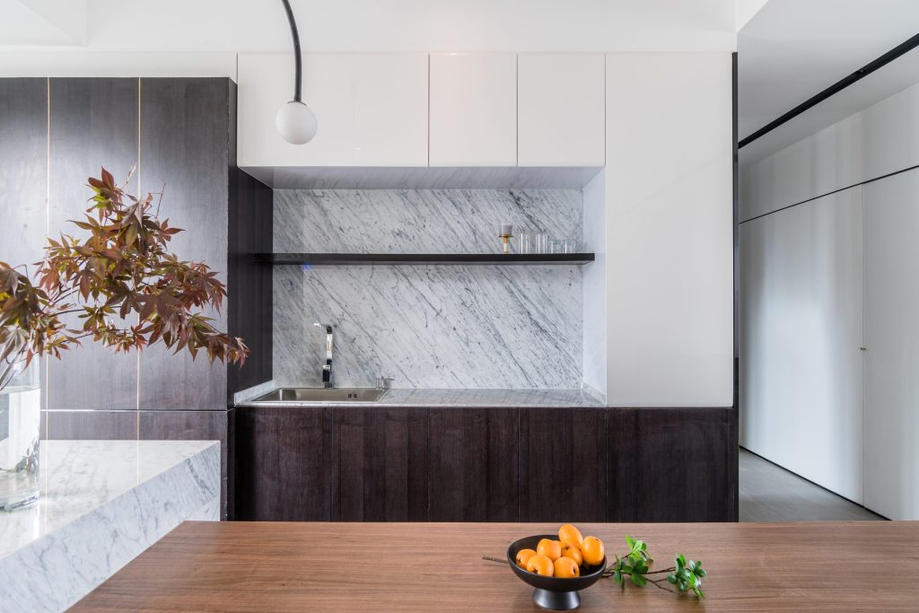 A marble splashback above a dark timber run with a wooden counter in front