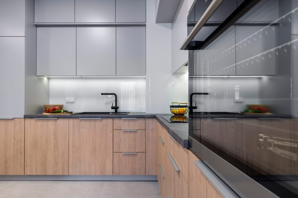 An oak kitchen run with a stone worktop and a black glass hob beside the sink