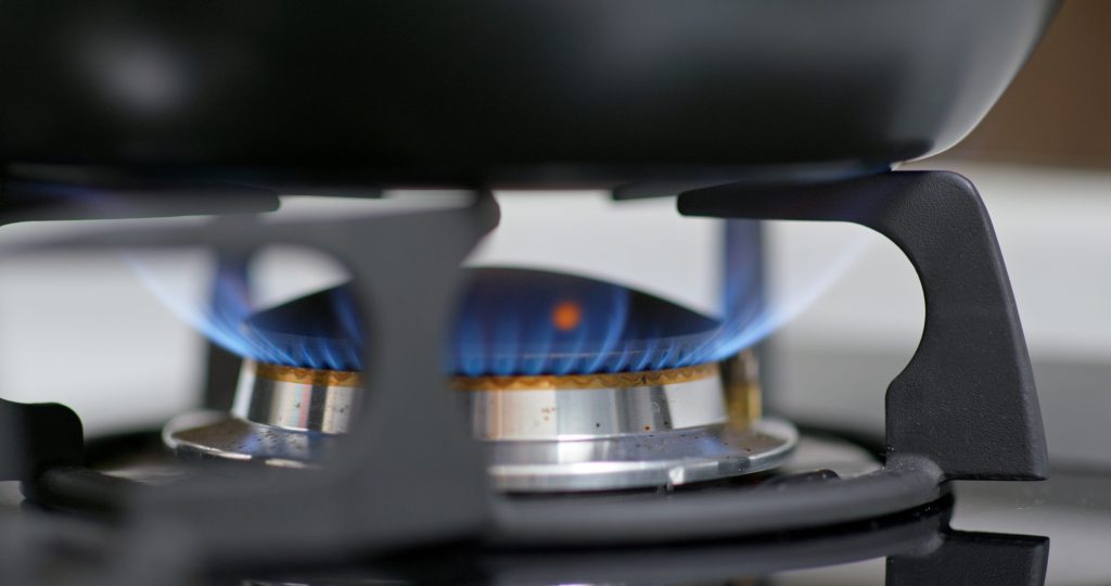 A burner ring alight with a clean blue flame on a stainless cooking surface