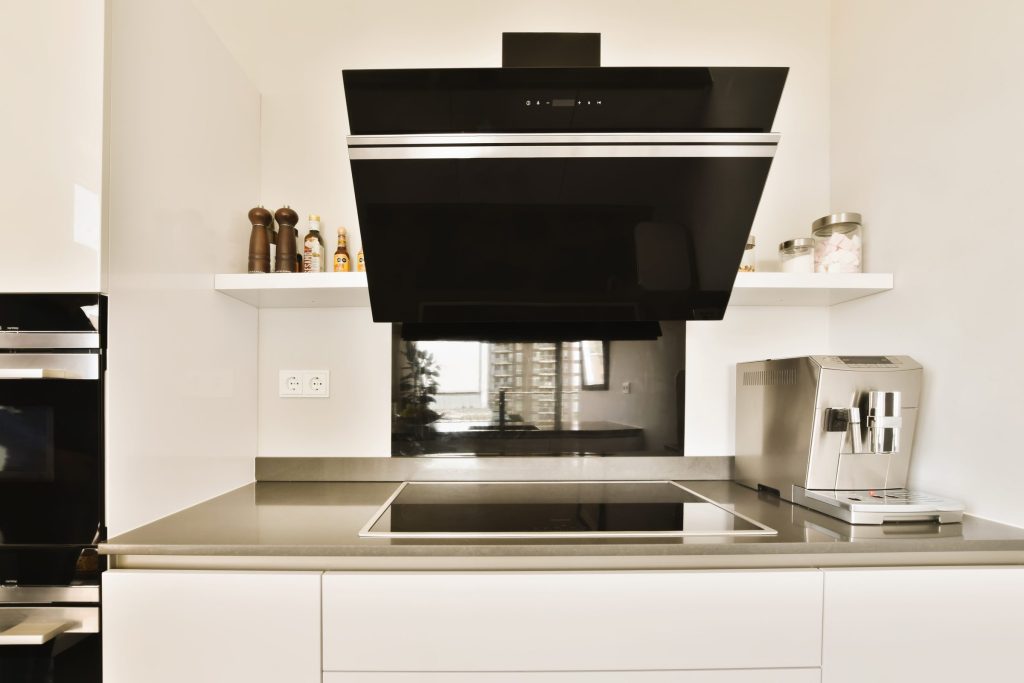 A black angled hood over an induction hob in a white gloss kitchen