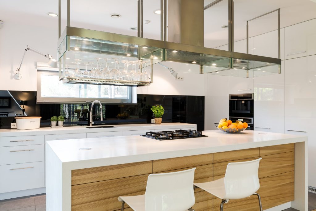 A wood-fronted island with a gas hob under a hanging glass rack