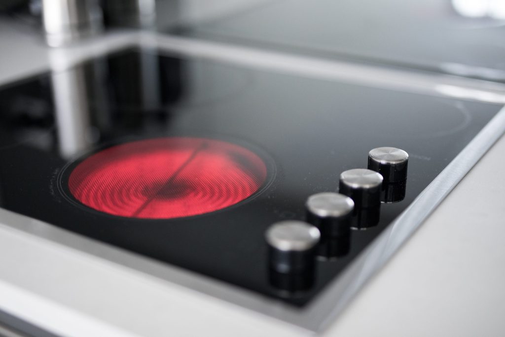 A radiant element glowing red on a black glass cooktop with control knobs alongside