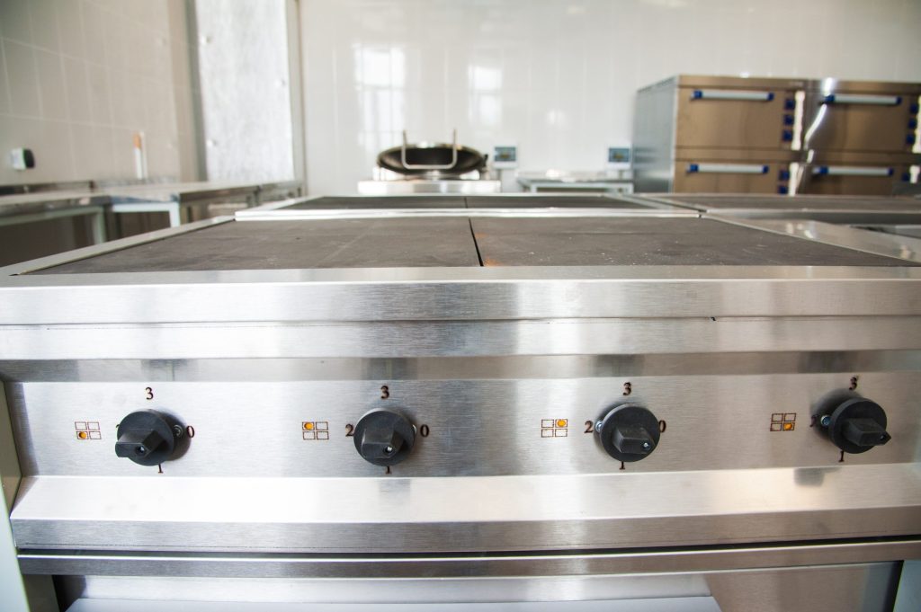 A wide stainless griddle plate with its control knobs below the front rail