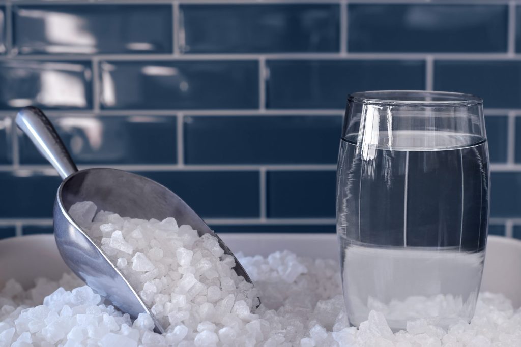 A scoop resting in crushed ice beside a tall glass of clear water