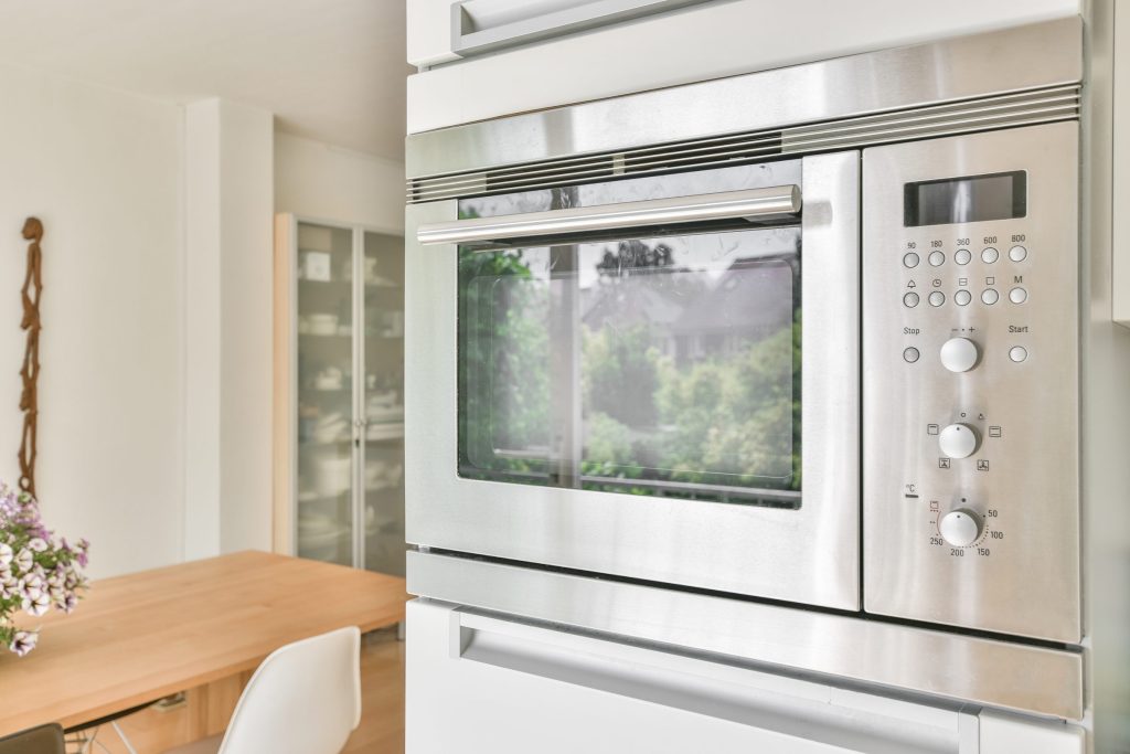 The keypad and dials of a built-in combination microwave oven beside its glass door
