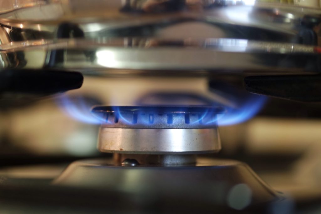 An open gas burner burning under a heavy cast grate
