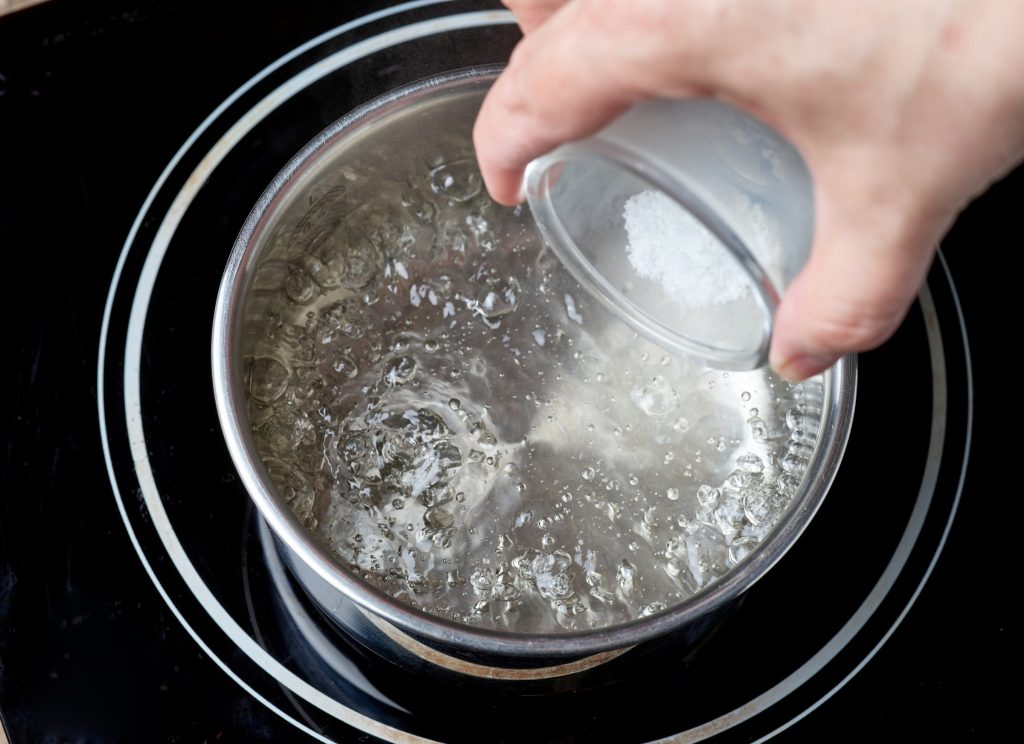 A measure of descaling powder going into a pan of simmering water