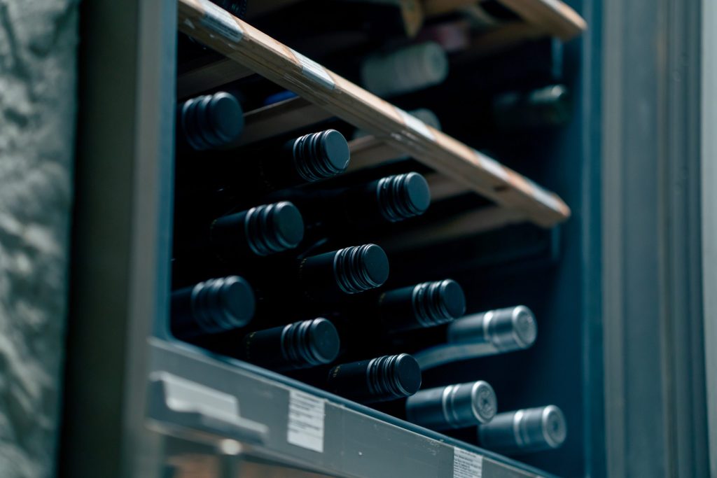 Bottles lying on the racks of a glass-fronted wine cabinet