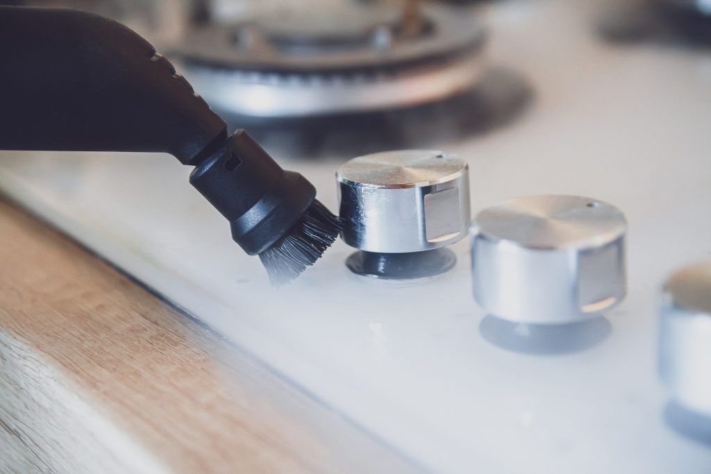 A brush head passing over the control knobs of a cooktop