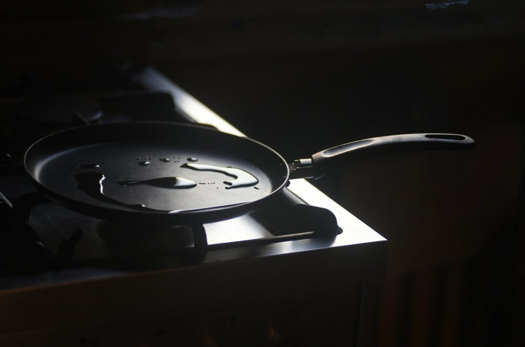 A pan resting on dark induction glass in a low-lit kitchen