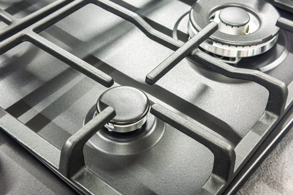 Two burner heads and their cast grates on a stainless cooktop