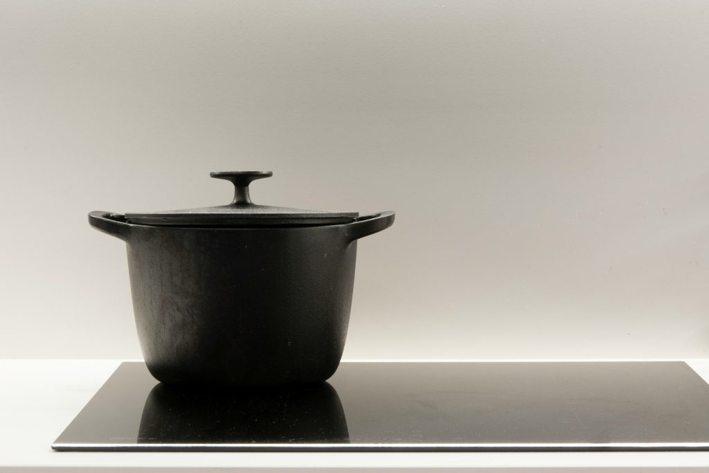 A black cast-iron casserole standing on an induction plate