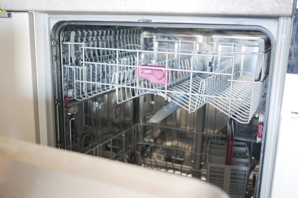 The silver racks of a dishwasher seen through its open door