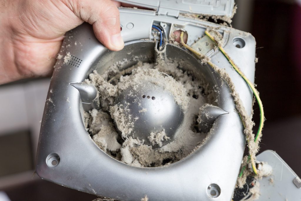 A blower wheel packed with dust and lint held in two hands