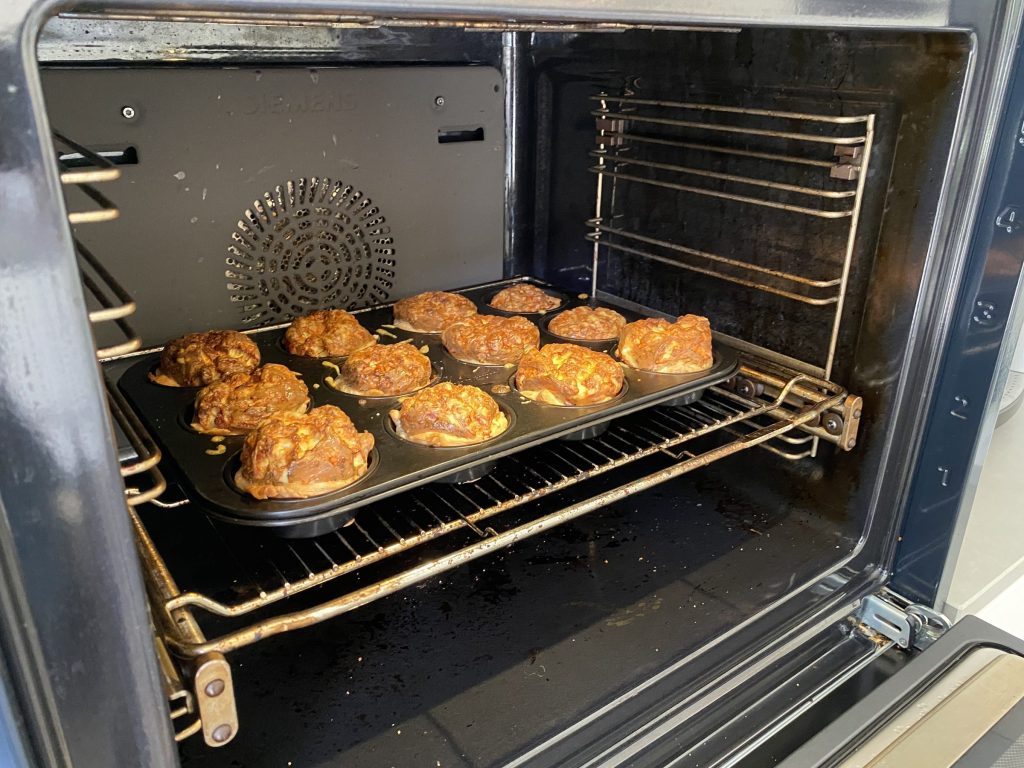 A tray of muffins on the rack of an oven with a soiled cavity
