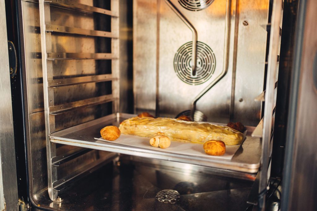 Pastries on a tray in a stainless oven cavity with the element visible above