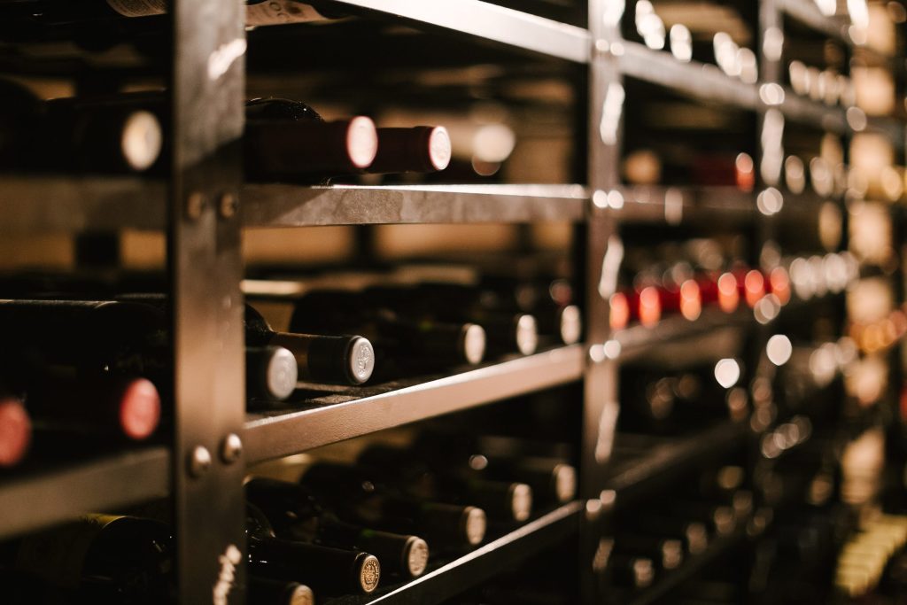 Rows of bottles lying on the lit shelves of a wine store