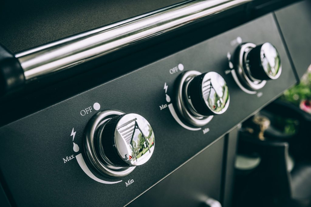 The control knobs of a built-in gas grill, marked from Min to Max with the ignition symbol beside each