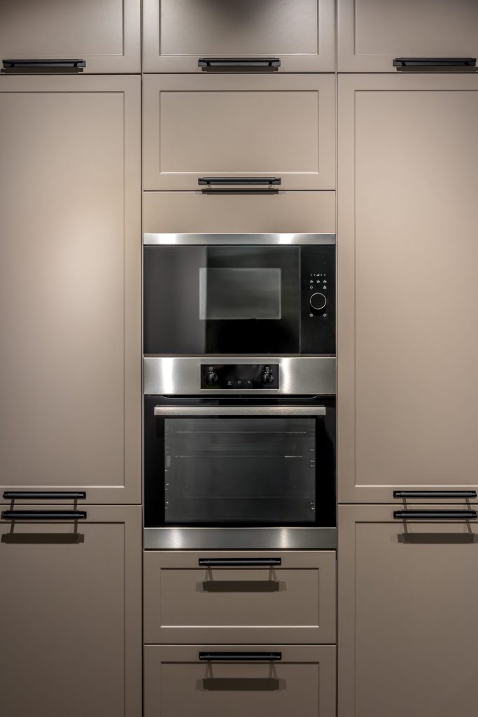 A stainless built-in oven and microwave stacked in a tall run of matte cabinetry